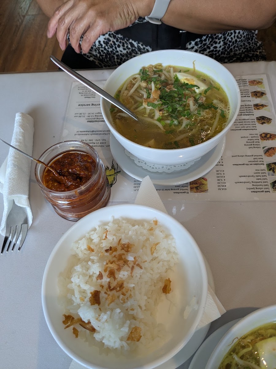 Kom soto ajam met witte rijst en een potje sambal ernaast.